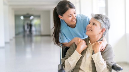 Pflegetagegeldversicherung: Ältere Frau im Rollstuhl mit Pflegerin